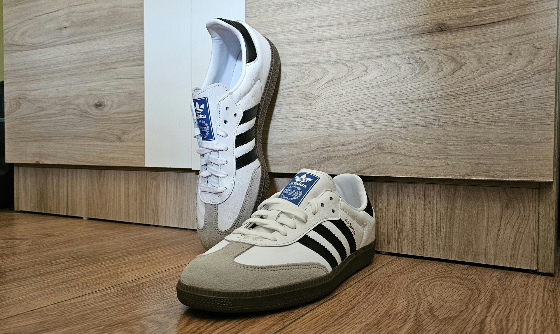 a pair of white and black shoes on a wooden floor